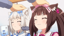 a person petting a cat girl 's head while another girl looks at a book