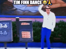 a man in a white shirt and blue pants is standing in front of a sign that says tim finn dance