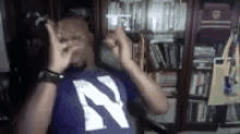 a man wearing a purple shirt with the letter n on it is making a horn sign .