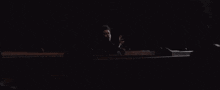 a man is sitting in a dark room talking on a cell phone
