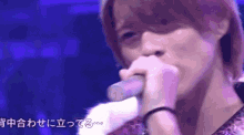 a close up of a person singing into a microphone with a blue background .