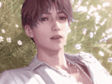 a man in a white shirt is laying in the grass with flowers behind him