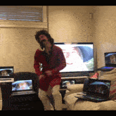 a man in a red jacket is dancing in front of a tv screen