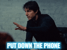 a man is sitting at a table with the words put down the phone above him
