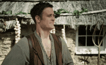 a man stands in front of a thatched roof