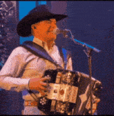 a man in a cowboy hat is singing into a microphone while playing an accordion that says " texas " on it