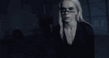 a group of people are dancing in a dark room in front of a light .