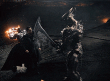 a man in a black cape is fighting a monster with a sword