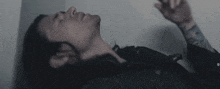 a man with long hair and a tattoo on his arm is laying down with his eyes closed