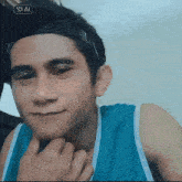 a young man wearing a headband and a blue tank top looks at the camera with a star ai icon above his head