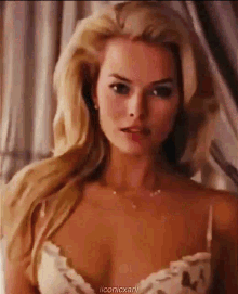 a woman with long blonde hair is wearing a white bra and necklace .