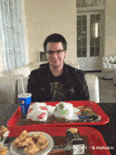 a man sitting at a table with a tray of food and a pepsi drink