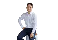 a man in a white shirt is sitting on a stool with his hands on his hips .
