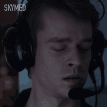 a man wearing headphones and a microphone with the word skymed on the bottom right