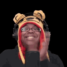 a woman wearing a tiger hat and headphones is standing in front of a microphone and smiling .