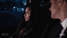 a woman sits in the back seat of a car next to a man in a suit with the word bet on the bottom