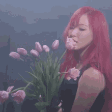 a woman with red hair is holding a bouquet of pink tulips in her mouth .
