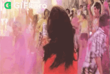 a woman in a red dress is dancing in front of a crowd of people at a party .