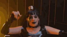a drag queen wearing black latex gloves and a choker is dancing