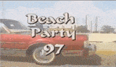 a red car is parked next to a sign that says beach party 97 .