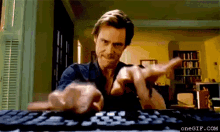 a man is typing on a keyboard with the website onegif.com in the background