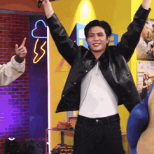 a man in a black leather jacket holds his arms up in the air