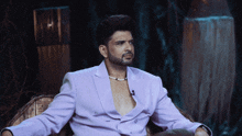a man in a purple suit is sitting in a chair with his arms outstretched