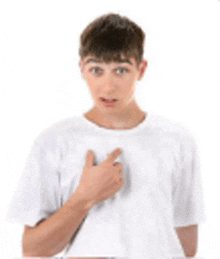 a young boy in a white t-shirt is pointing at his chest .
