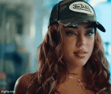 a woman wearing a von dutch hat looks at the camera