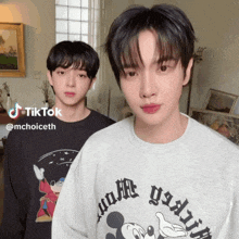 two young men are standing next to each other and one of them is wearing a mickey mouse shirt