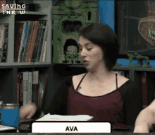 a woman is sitting at a table with a sign that says ava on it .