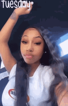 a woman is taking a selfie with her hand in the air while wearing a white shirt .
