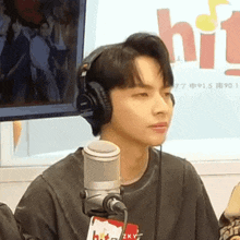 a young man wearing headphones is sitting in front of a microphone in a radio station .