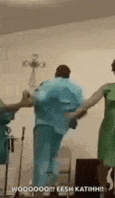 a man and two women are dancing together in a room while holding hands .