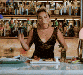 a woman in a black lace top stands in front of a bar
