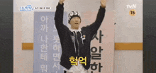 a man is standing in front of a sign with his arms in the air and making a funny face .