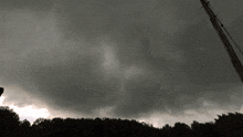 a dark cloudy sky with a few trees in the foreground
