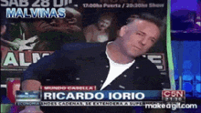 a man is sitting in front of a screen that says ricardo iorio on it
