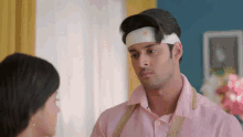 a man with a bandage on his head looks at a woman in a pink shirt