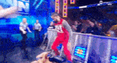 a man in a red jersey and red pants is walking across a fence .