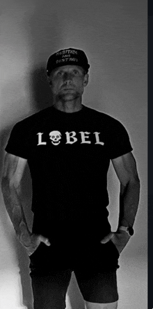 a man wearing a black label t-shirt and a black hat