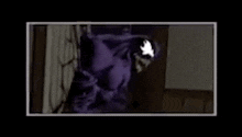a purple monster is standing in a dark room with a white eye .