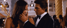 a man in a tuxedo is touching the face of a woman