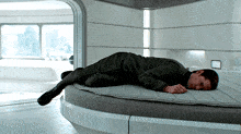 a man is laying on a round bed with his head on the mattress