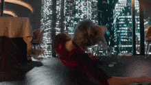 a woman is laying on the floor in front of a city skyline at night