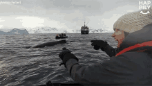 a woman is pointing at a whale while a boat is in the background and the word hap is on the bottom