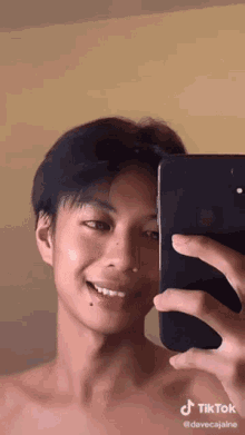 a young man is taking a selfie in front of a mirror with his cell phone .