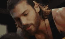 a man with long hair and a beard wearing a black tank top .
