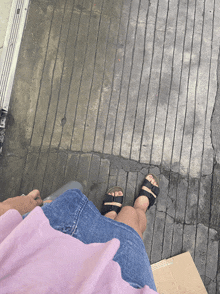 a person standing on a concrete floor with their feet on a cardboard box