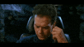 a man is sitting in a chair with his hand on his face